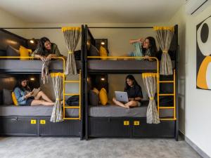 three girls sitting on bunk beds in a room at The Hosteller Bam Vagamon in Vagamon