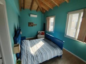 a bedroom with a bed with a blue wall at Ostello Casa Peroni in Castelnuovo Bocca dʼAdda +25 photos
