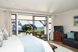 a bedroom with a bed and a couch and a television at Crawfords Beach Lodge in Chintsa