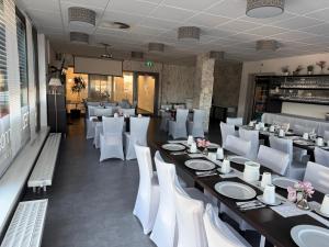 ein Restaurant mit einem langen Tisch und weißen Stühlen in der Unterkunft Hotel Efcannos in Vechelde