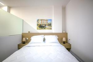 a bedroom with a large white bed with two lamps at Denis Studios Durres in Durrës