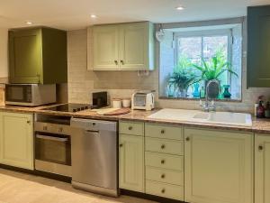 a kitchen with green cabinets and a sink and a window at 2 Bed in Chipping Norton oc-73904 in Swerford +16 photos