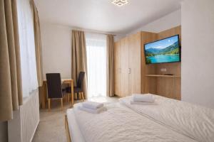 a hotel room with a bed and a television on a wall at Seehaus Gori in Maria Wörth