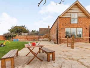 a patio with a table and benches in front of a brick building at 3 Bed in Pershore oc-86760 in Eckington