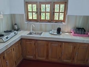 a kitchen with wooden cabinets and a sink at Ramanayaka Serenity Villa in Bandarawela