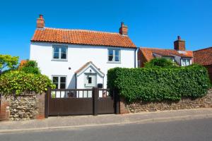 a white house with a fence and bushes at 3 Bed in Brancaster oc-2153 in Brancaster