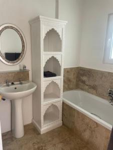 a bathroom with a sink and a white shelf next to a bath tub at La Jolie Dauphine Guest House in Franschhoek +15 photos