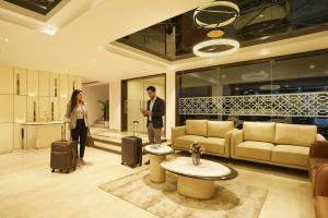 a man and woman standing in a living room with luggage at Liza Royale Hotel Near Chennai central Railway Station in Chennai