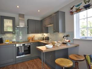 a kitchen with gray cabinets and a counter with stools at 1 Bed in Banbury oc-57103 in Upper Brailes