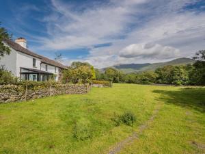 a white house with a stone wall and a grass field at 4 Bed in Broughton-in-furness oc-sz183 in Ulpha