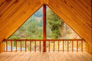 a room with a large window in a wooden cabin at Riverside Mudhouse Duplex Cottage by Kahani in Jibhi