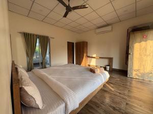 a bedroom with a large bed with a ceiling fan at Vanray Farm And Resort in Talala