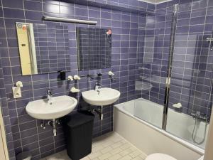 a blue tiled bathroom with two sinks and a bath tub at Casa Ghentele in Blankenberge +15 photos