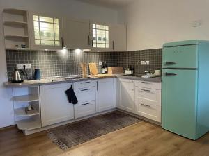 a kitchen with white cabinets and a blue refrigerator at Chalupa Lindenberg in Jestrabi V Krkonosich