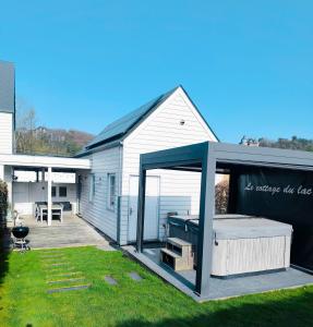 a house with a covered patio with a hot tub at Cottage du Lac Studio in Nivezé