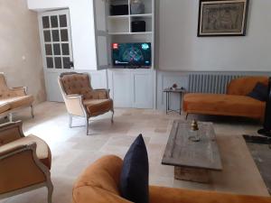 a living room with couches and a tv at Maison d'Orion in La Réole