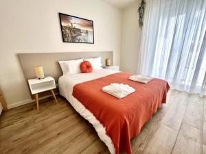 a bedroom with a large bed with a red blanket at Cor de Mar • Pátio • 2 Quartos • Centro Histórico in Peniche