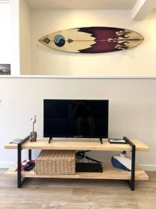 a surfboard is hanging on a wall above a television at Cor de Mar • Pátio • 2 Quartos • Centro Histórico in Peniche