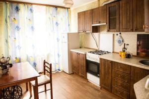 cocina con armarios de madera, mesa y fogones en Apartments on Kirova 32 en Rybinsk