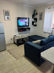 a living room with a blue couch and a flat screen tv at Seabreeze Accommodation in Lüderitz