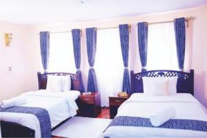 a bedroom with two beds and blue curtains at Orchard Manor in Nairobi