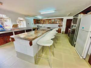 a kitchen with a large island with white stools at Orchard Manor in Nairobi