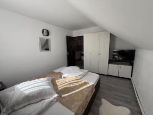 a white bedroom with a bed and a television at Apartament Ral in Arieşeni