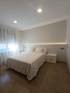 a white bedroom with a large bed and a window at Apartamentos Elvira Valderrobres in Valderrobres