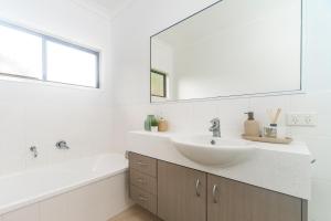 a bathroom with a sink and a tub and a mirror at Curlew Cove in Airlie Beach +5 photos