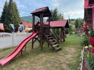 a playground with a slide in a yard at Apartament Ral in Arieşeni
