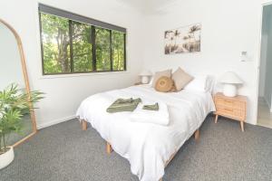 a bedroom with a large white bed with towels on it at Curlew Cove in Airlie Beach