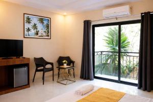a bedroom with a large window and a television at Hotel Centro in Calangute