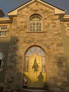a yellow door on the side of a stone building at Cloonacauneen House in Balnacart