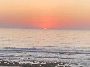a sunset over the ocean with the sun in the horizon at Riad mama aicha in Asilah