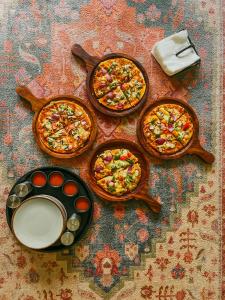 four plates of pizzas sitting on a table at Private Mudhouse Duplex Cottage by Kahani in Jibhi