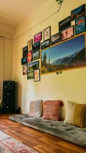 a couch in a room with pictures on the wall at Private Mudhouse Duplex Cottage by Kahani in Jibhi