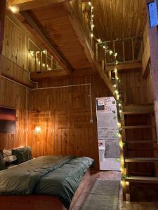 a bedroom with a bed in a wooden room with lights at Private Mudhouse Duplex Cottage by Kahani in Jibhi