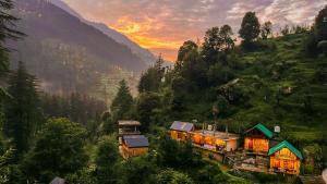 a house on a hill with the sunset in the background at Private Mudhouse Duplex Cottage by Kahani in Jibhi