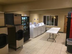 a kitchen with refrigerators and a table and a chair at Travelodge by Wyndham Hawthorne in Hawthorne