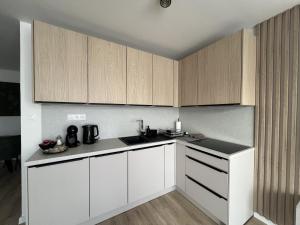 a kitchen with white counters and wooden cabinets at Apartmán LÝRA Trenčín in Trenčín