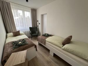 a room with two beds and a chair and a window at Apartmán LÝRA Trenčín in Trenčín