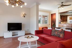 a living room with a red couch and a tv at Phoceus Poolfront Grande Villa in Palaia Fokaia