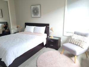 a bedroom with a large bed and a chair at Cosy Private Modern Flat in Epping