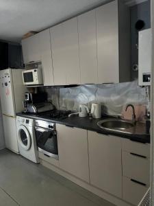 a kitchen with white cabinets and a sink and a stove at Дідова Хата in Sheshory +6 photos