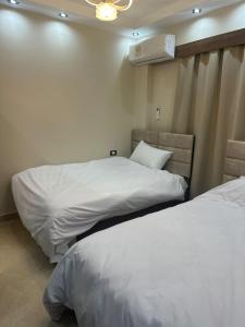 two beds in a room with white sheets and a fan at Sharm Glow Villa in Sharm El Sheikh