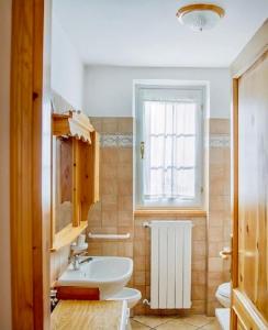 a bathroom with a sink and a toilet and a window at Ca' Maria - Casa in Scalve in Schilpario