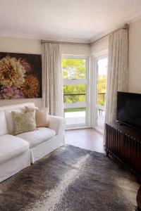 a living room with a white couch and a television at The Gables Boutique Hotel in Chintsa