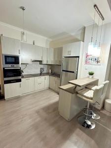 a kitchen with white cabinets and a table and a refrigerator at BartokLux in Budapest