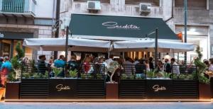 a crowd of people standing outside a restaurant with umbrellas at Chiave di Volta luxury suite e rooms in Palermo