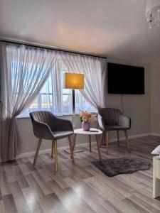 a living room with two chairs and a table and a tv at Atpūta Mālpilī in Mālpils +13 photos